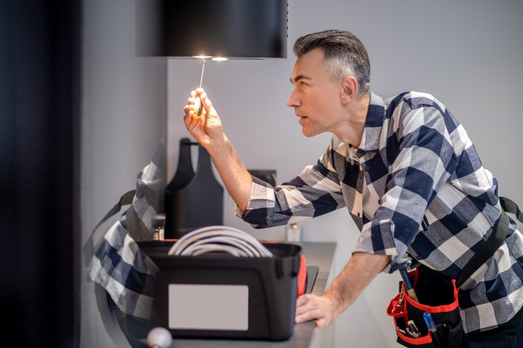 renovation-profile-concentrated-man-touching-screwdriver-lamp-kitchen-range-hood (1)